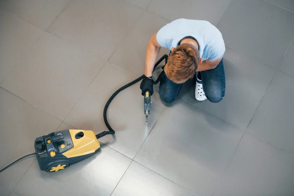 man restoring tile and grout in school